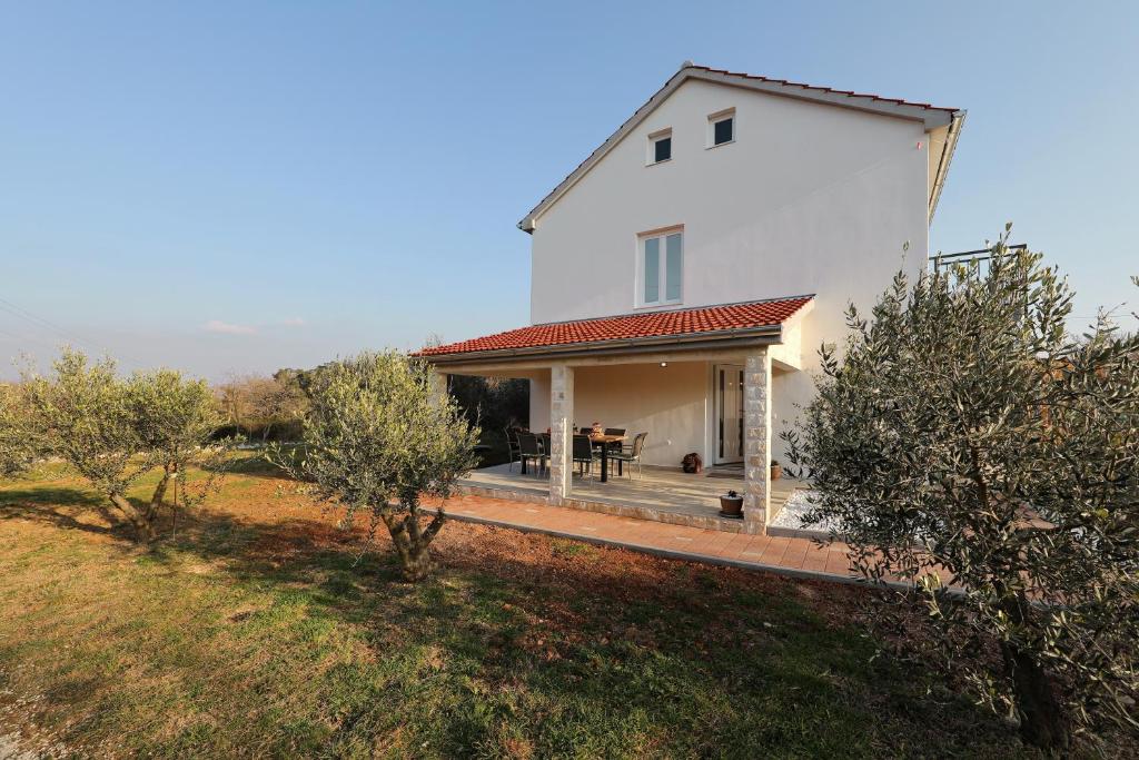 una casa bianca con un portico su un campo di Holiday Home Hrast a Debeljak