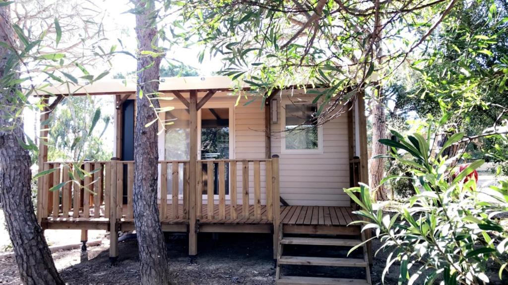 a small wooden house with a porch in the woods at Camping la Croix du Sud in Saint-Tropez