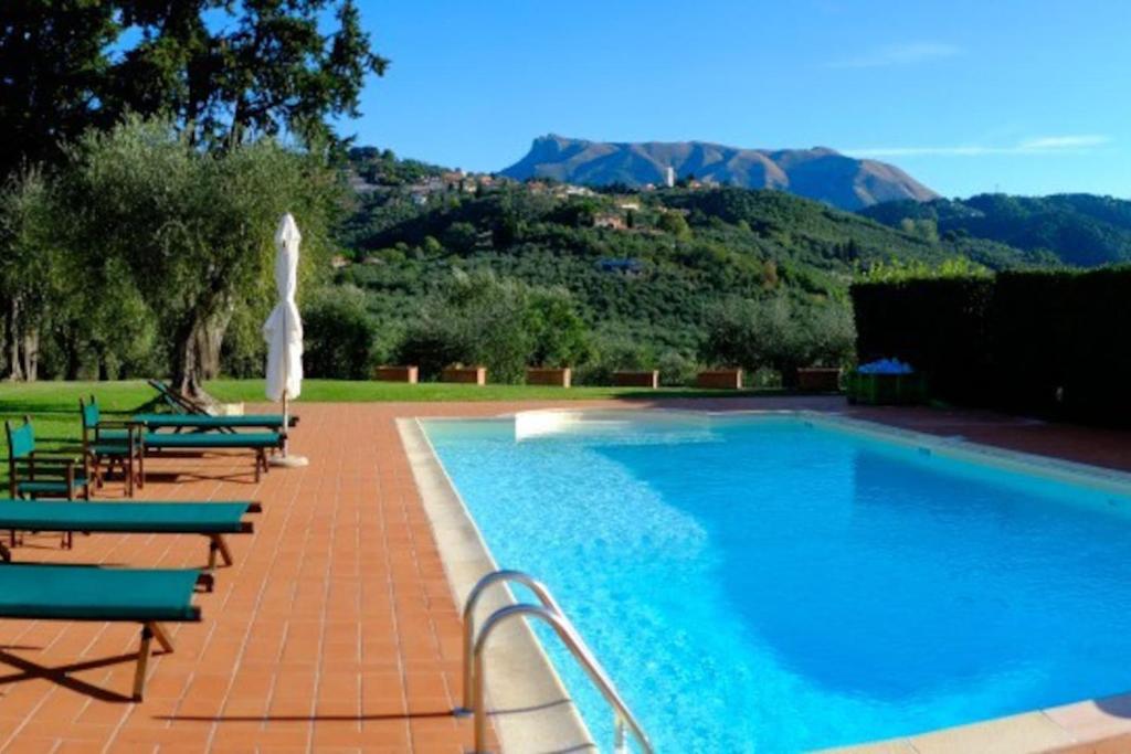 a swimming pool with chairs and an umbrella at Villa Cenami Apartments with BIG POOL in Massarosa