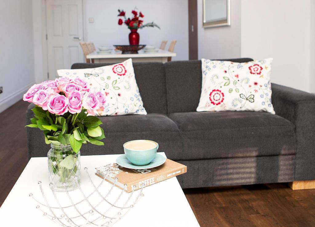 a living room with a couch and a vase of flowers on a table at Apt 3, Trafalgar Sq Duplex, 3rd & 4th floor by Indigo Flats in London