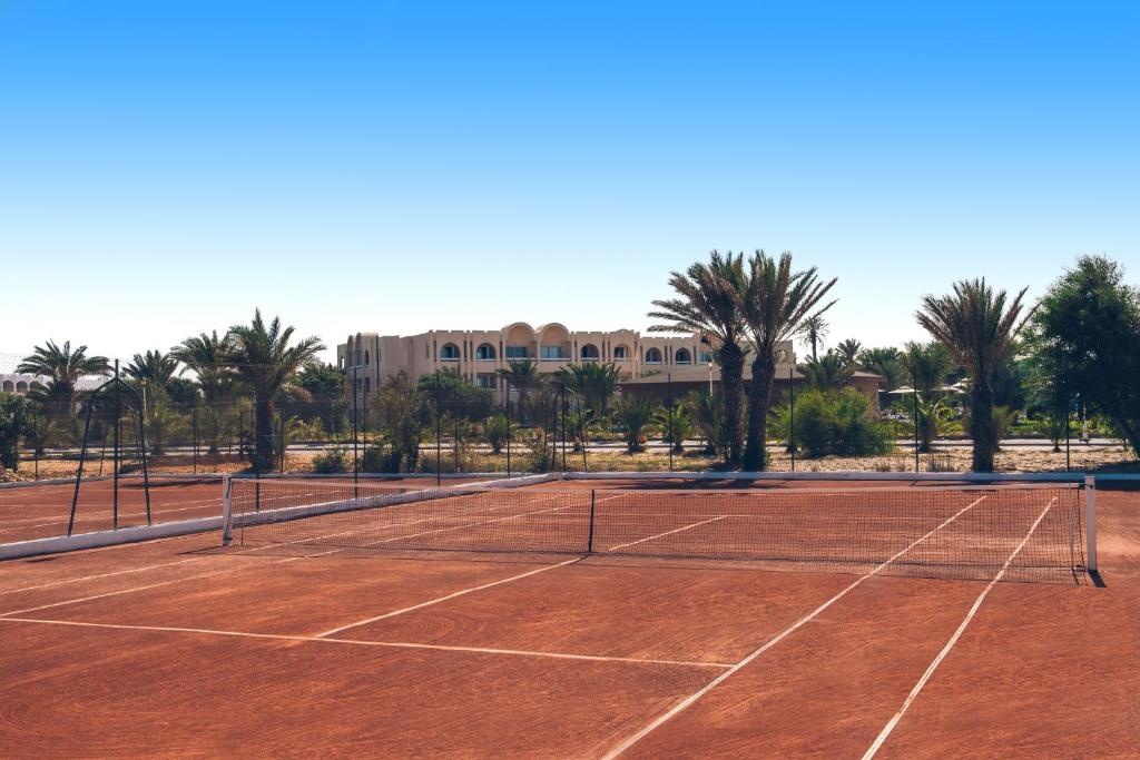 a tennis court with palm trees and a building at Iberostar Waves Mehari Djerba in Taguermess
