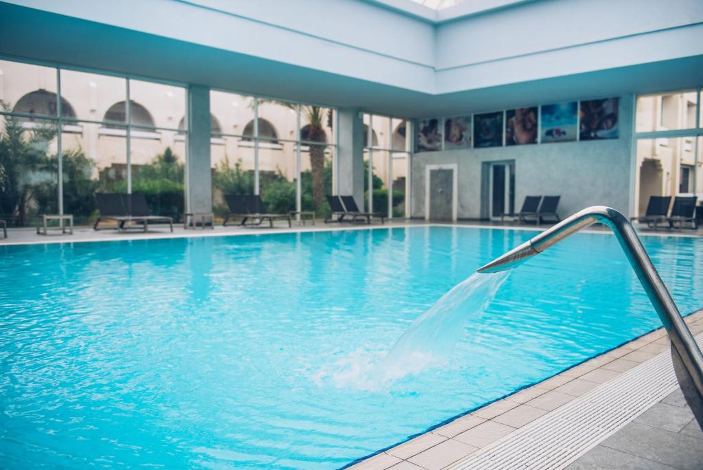 a swimming pool with a fountain in a building at Iberostar Waves Mehari Djerba in Taguermess