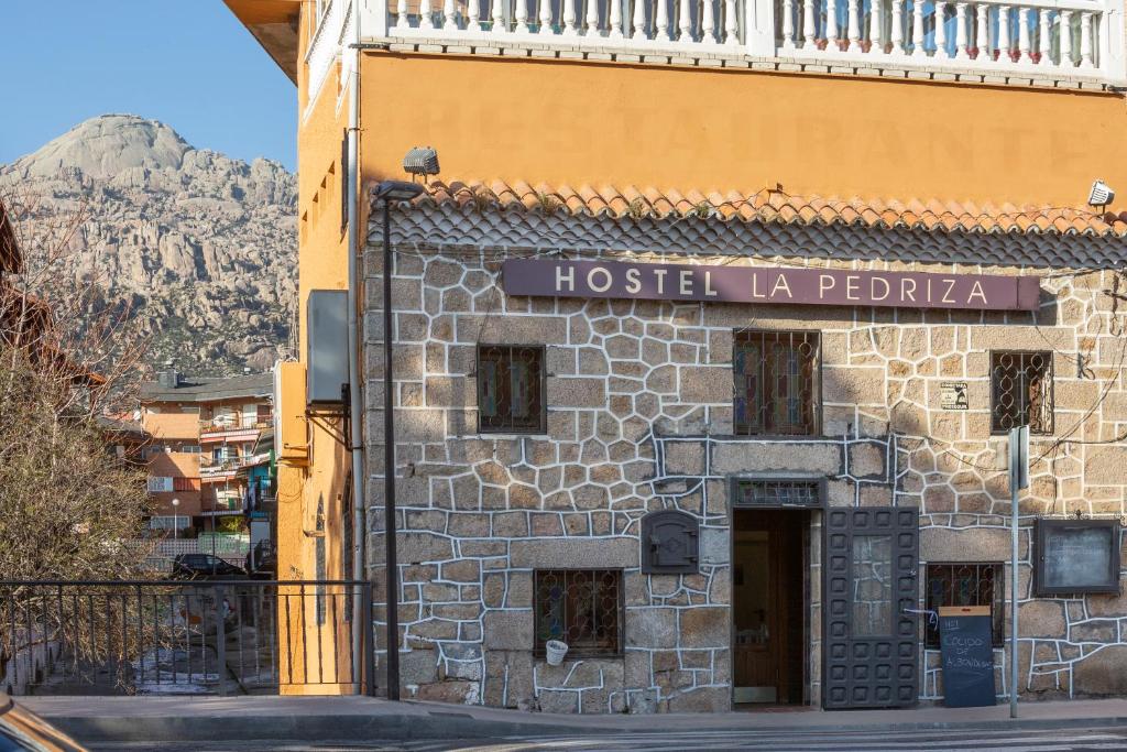 un bâtiment avec un panneau indiquant l'auberge de jeunesse la pedra dans l'établissement Hostel La Pedriza, à Manzanares el Real