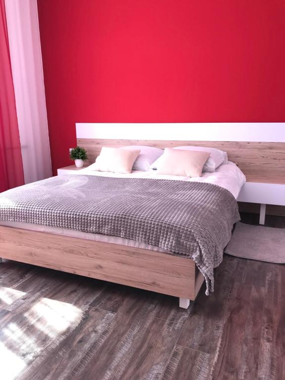 Schlafzimmer mit einem Holzbett mit einer roten Wand in der Unterkunft Apartment Ternopil in Ternopil