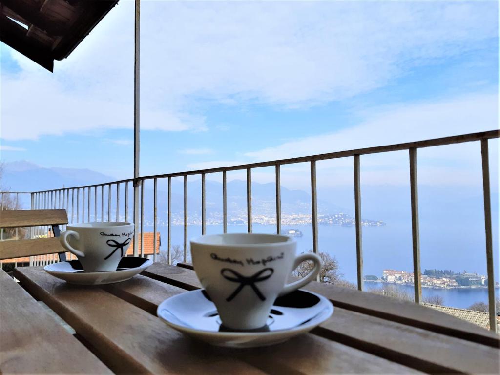 two coffee cups sitting on a table on a balcony at Le Camere Della Vecchia Osteria in Stresa