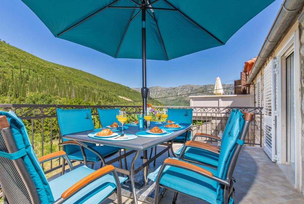 - une table avec des chaises et un parasol sur le balcon dans l'établissement Villa Sweet Home, à Mokošica