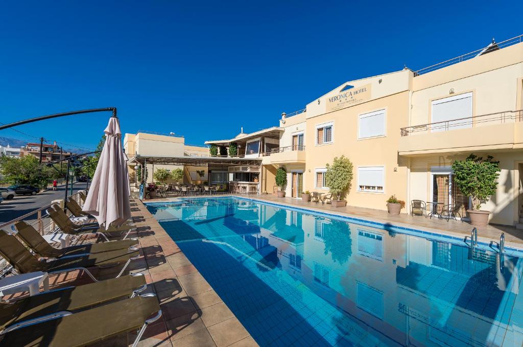 a swimming pool with chairs and an umbrella next to a building at Veronica Hotel in Kato Daratso