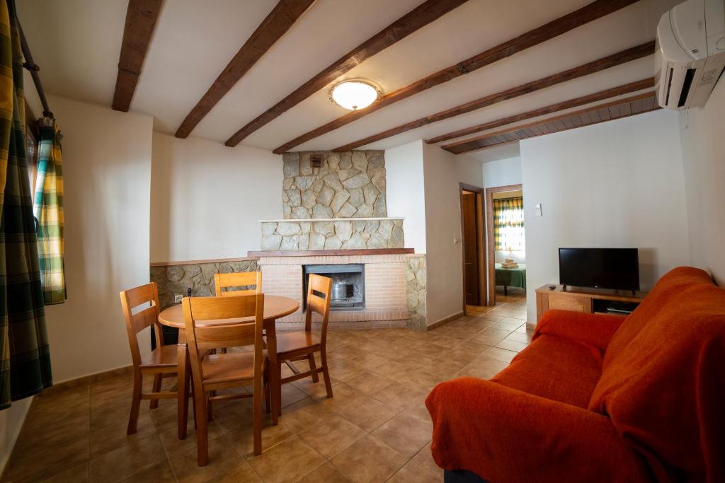 Una sala de estar con una mesa y una chimenea. en Apartamentos Berrocal, en Alcalá del Júcar
