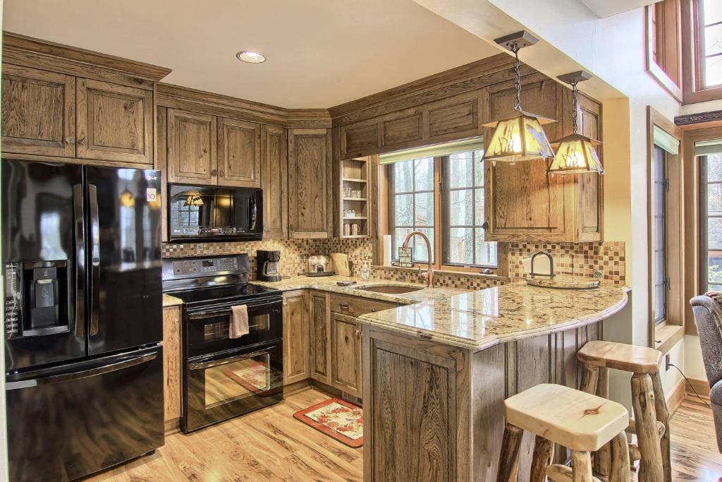 a kitchen with wooden cabinets and a black refrigerator at 734 Disciples Village Condo in Boyne Falls