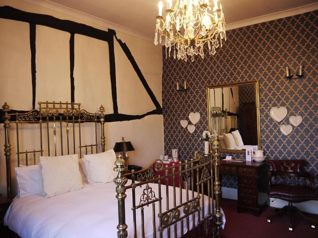a bedroom with a bed and a mirror and a chandelier at The Bell Hotel in Winslow