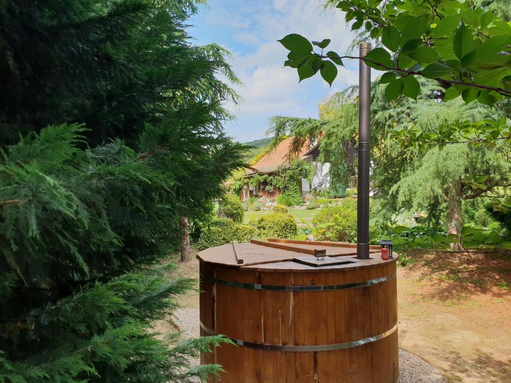 ein Holzfass in einem Garten mit einem Haus im Hintergrund in der Unterkunft Aralica Parasztház in Siklós