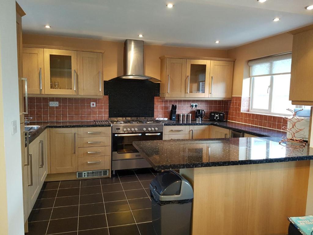 a kitchen with wooden cabinets and a stove top oven at Moorland House in Syston