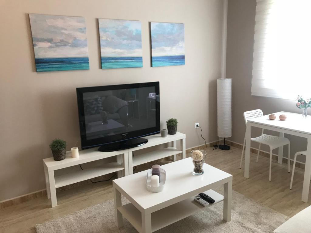 salon z telewizorem z płaskim ekranem i stołami w obiekcie Apartamento DELUXE Benalmádena w mieście Benalmádena