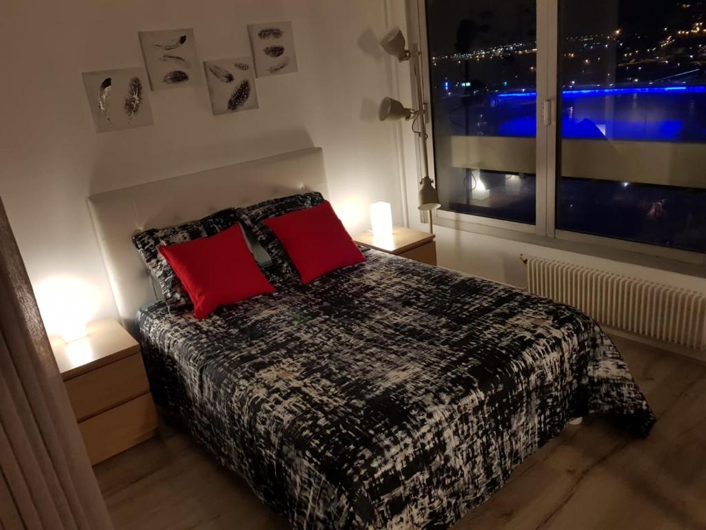 Un dormitorio con una cama con almohadas rojas y una ventana en Hirondelle de Rouen, en Rouen