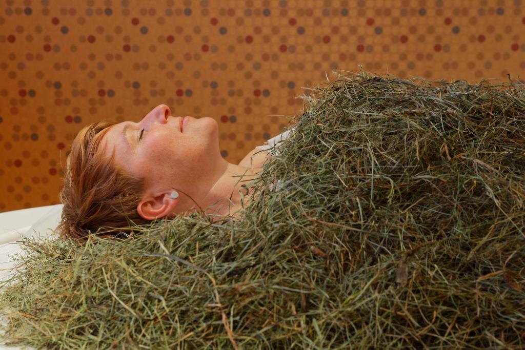 a woman is laying in a pile of grass at Berg-Spa & Hotel Zamangspitze in Sankt Gallenkirch