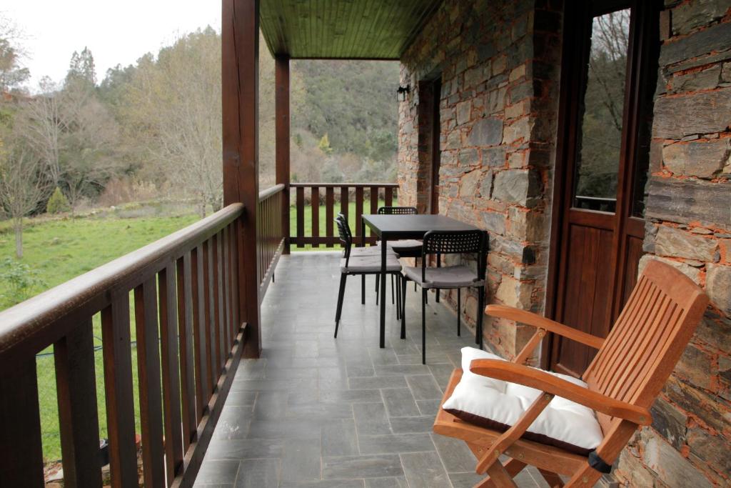 a porch with chairs and a table on it at Casas do Rio in Pampilhosa da Serra