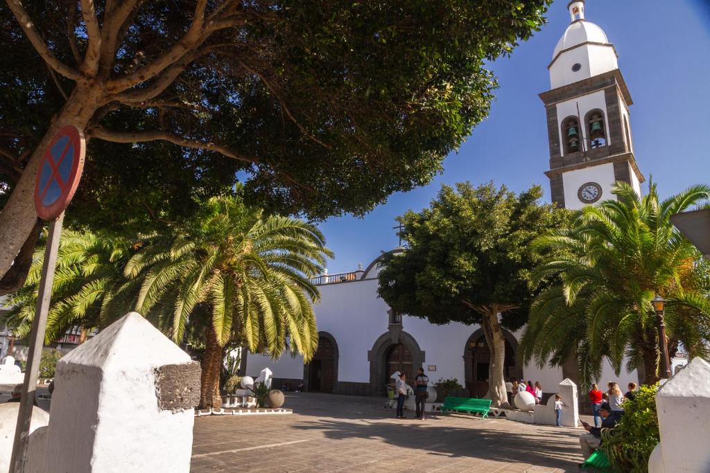 a church with a clock tower with palm trees at Rooms & Suites Loft 2G Deluxe Edition Arrecife in Arrecife