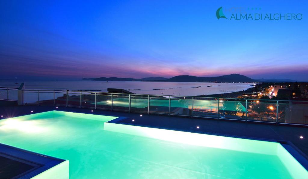 a swimming pool on top of a building at night at Alma di Alghero Hotel in Alghero