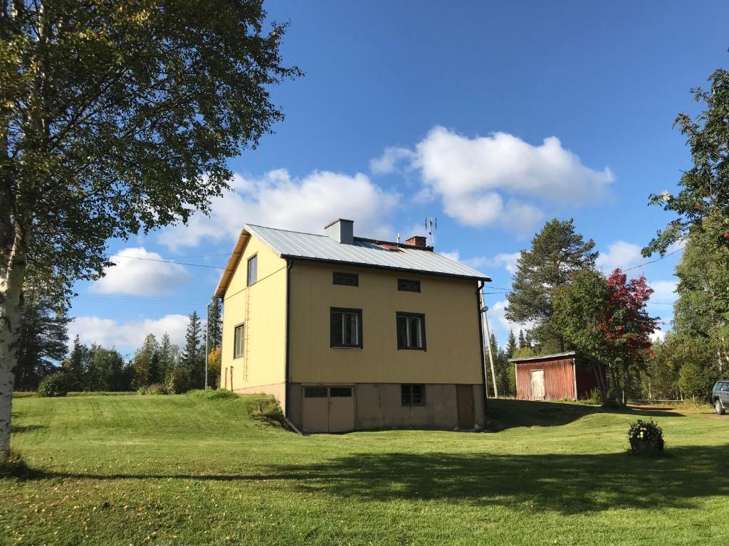 une grande maison jaune sur un champ herbeux dans l'établissement SÄHKÖPIRTTI SALMIVAARA, à Salla