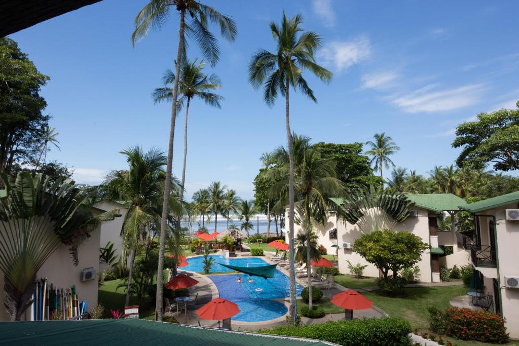 Blick auf den Pool in einem Resort mit Palmen in der Unterkunft Club del Mar Oceanfront in Jacó