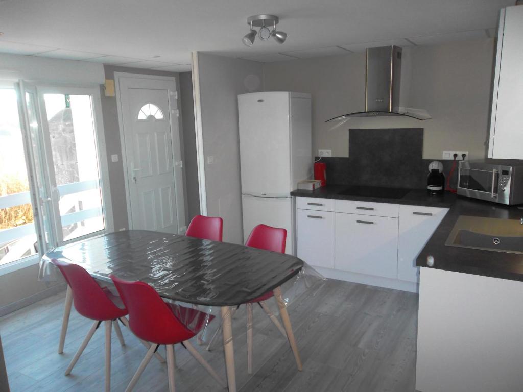 a kitchen with a table and red chairs in it at Appartement au centre du tholy pour 5 personnes maximum in Le Tholy