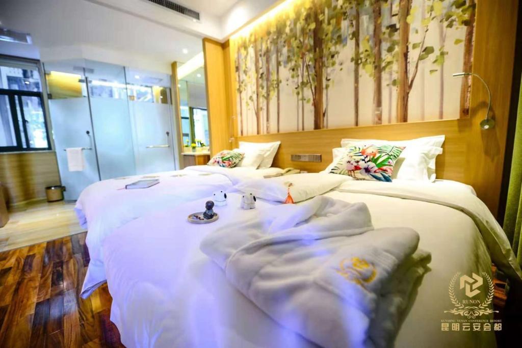 due letti in una camera d'albergo con lenzuola bianche di Yun'an Huidu Hotel a Kunming