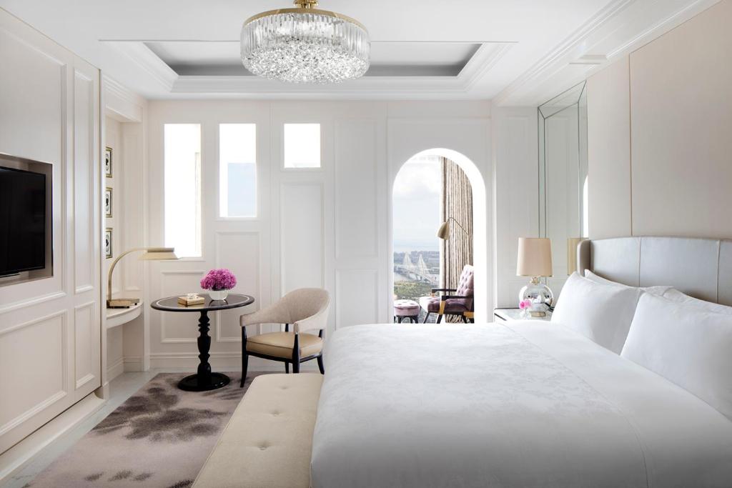 a white bedroom with a large bed and a table at The Langham Haikou in Haikou