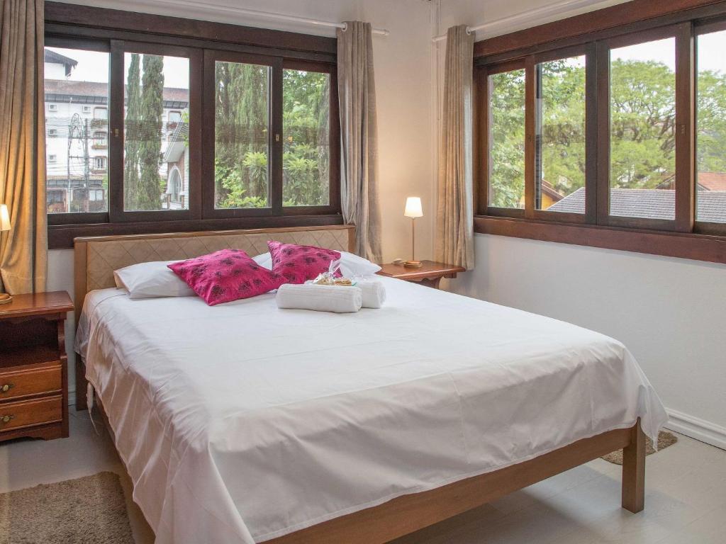 1 dormitorio con 1 cama blanca grande y ventanas en LOCAR-IN GRAMADO - Loft a 50 m da Rua Coberta, en Gramado