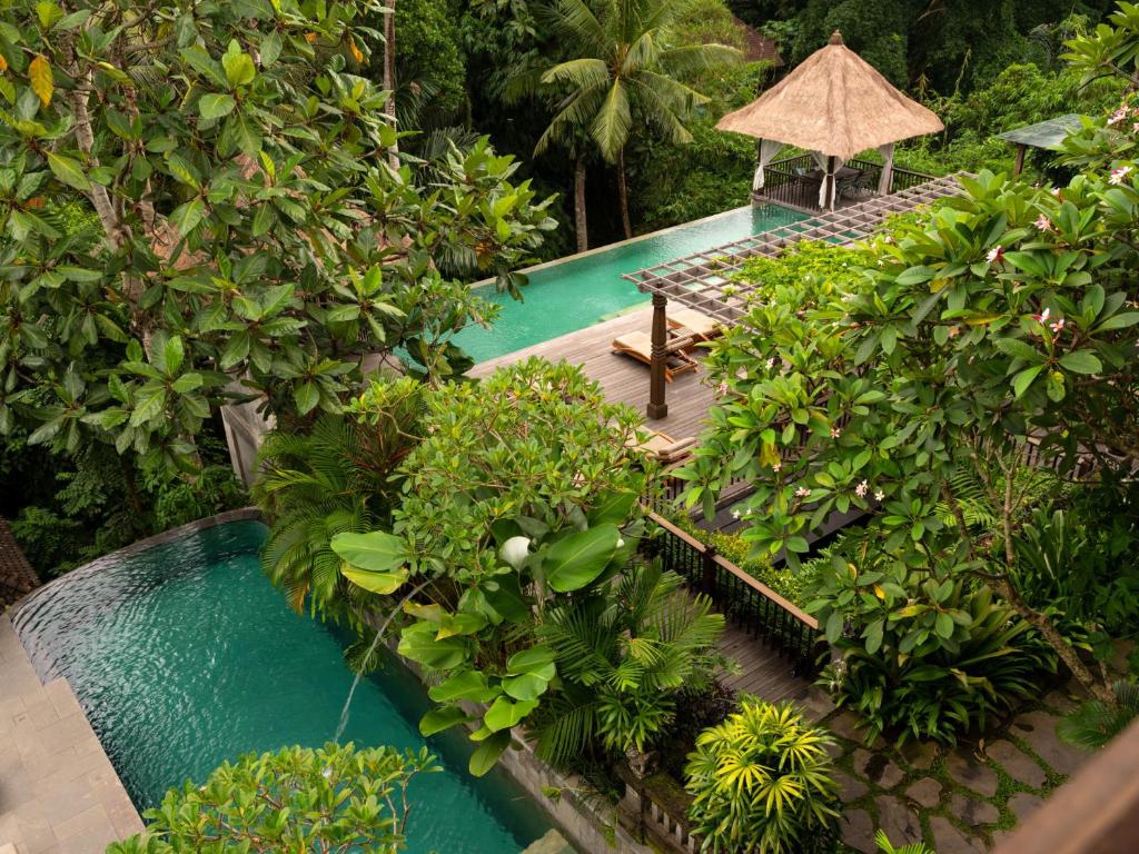 a garden area with a pool and trees at Adiwana Resort Jembawan in Ubud