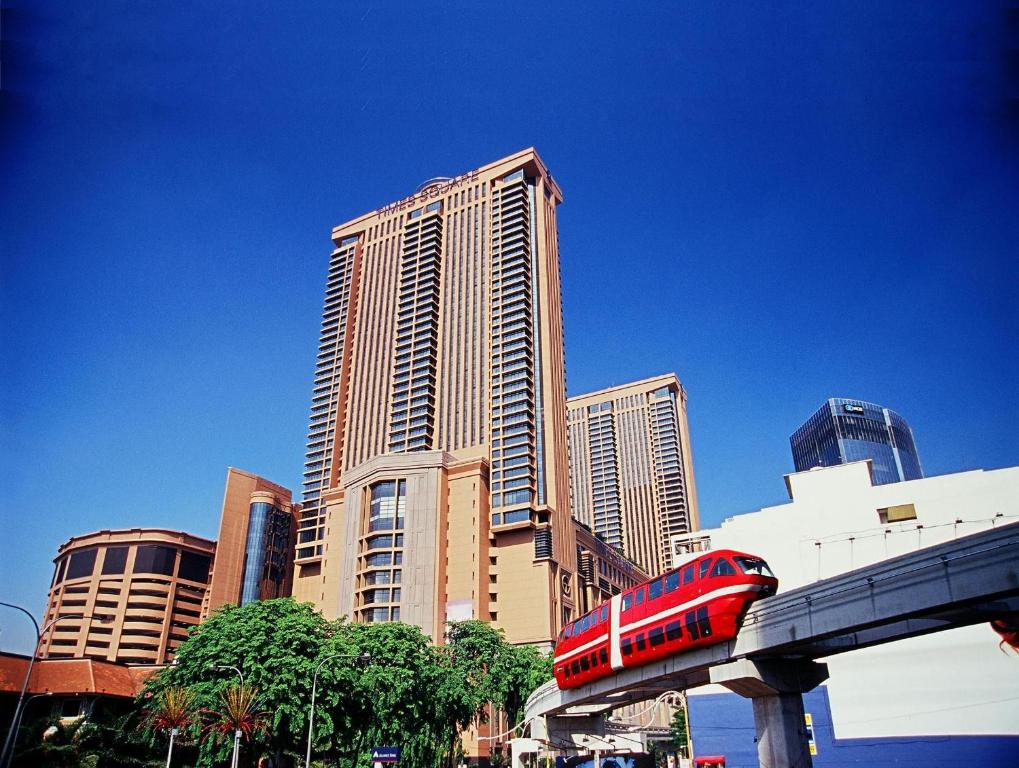 a red train on a track in front of tall buildings at Better Residence Suite at Times Square KL in Kuala Lumpur