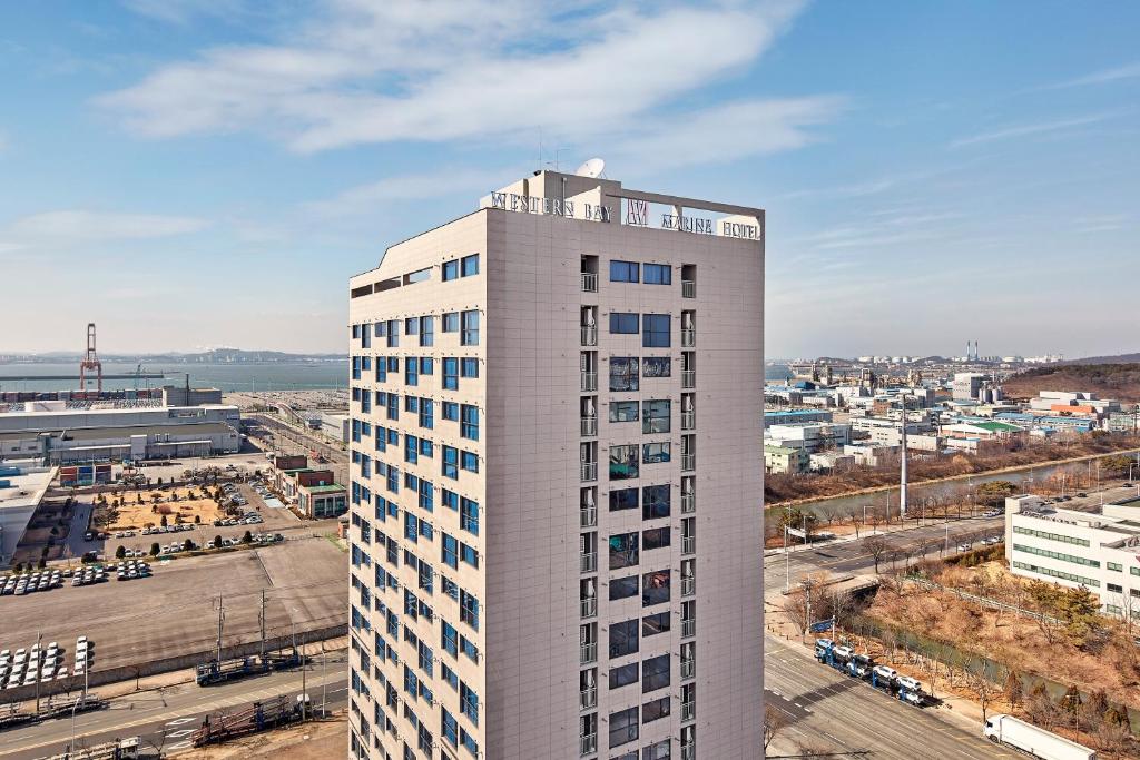 un edificio blanco alto con una ciudad en el fondo en Western Bay Marina Hotel en Pyeongtaek