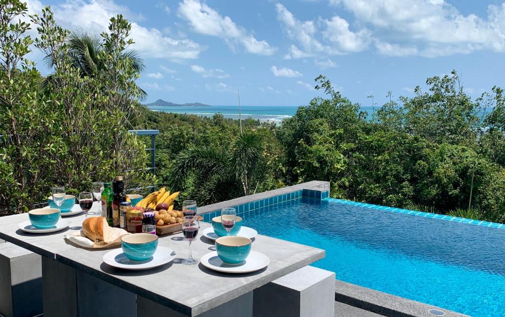 einen Tisch mit Speisen und Getränken neben einem Pool in der Unterkunft Sky Villa Seren with free car in Laem Set Beach