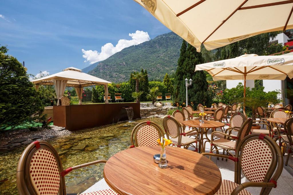 een openluchtrestaurant met tafels, stoelen en parasols bij Panorama Hotel Nocturnes in Naturno