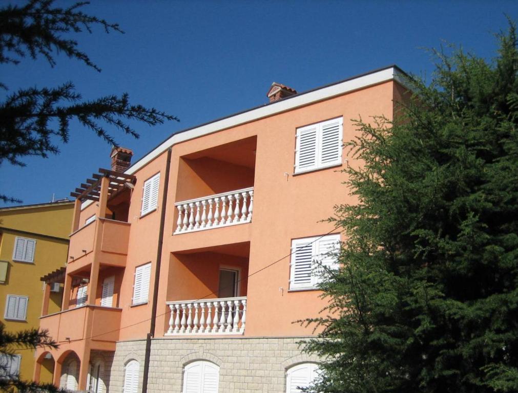 a orange building with white windows and a tree at Guest House Mare e Monti in Rabac