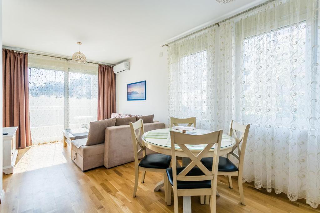 een woonkamer met een tafel en stoelen en een bank bij Apartments LORA Cetinjska in Budva