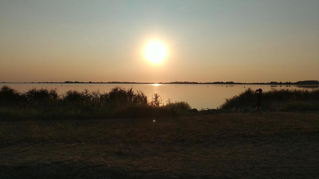 un coucher de soleil sur un lac avec le soleil dans le ciel dans l'établissement Ostseesonne, à Wiek auf Rügen