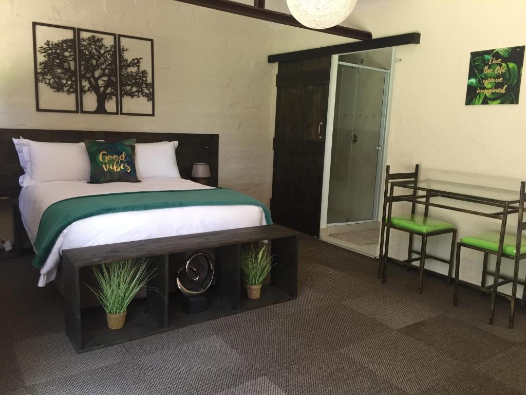 1 dormitorio con cama, mesa y espejo en TreeTopia Guesthouse, en Benoni