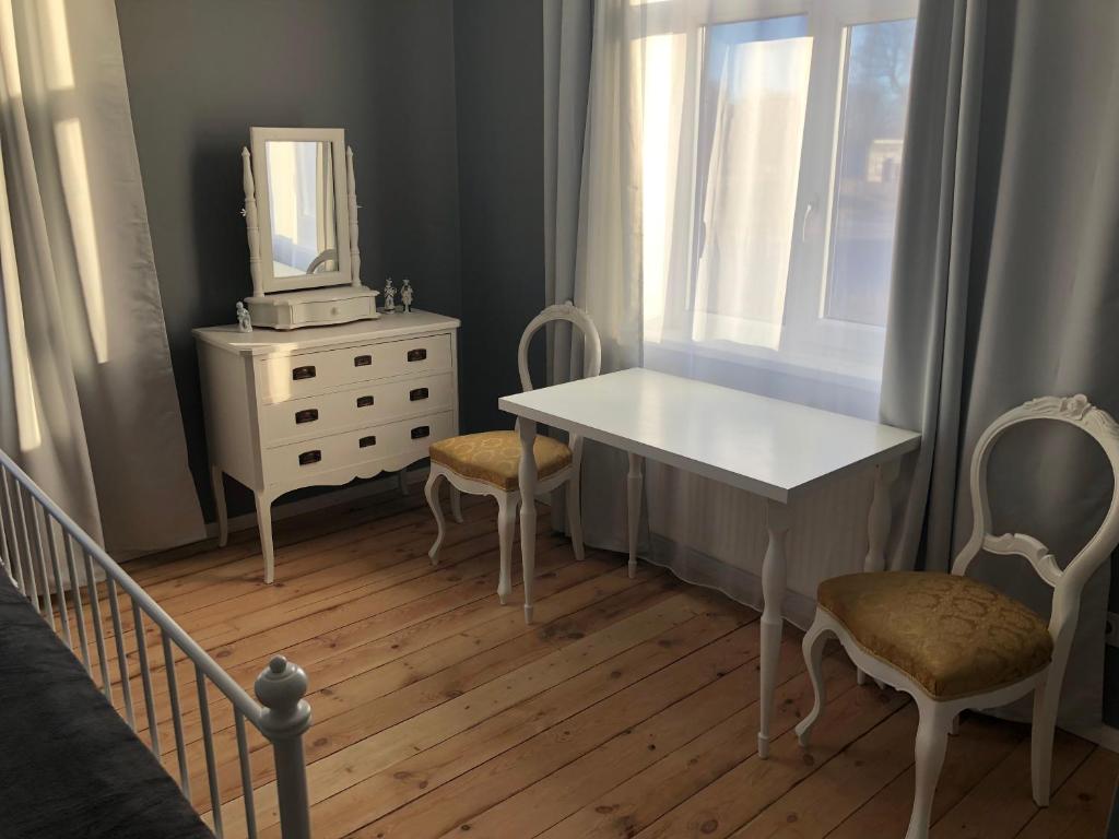Skrunda Apartments Elandrum في سكروندا: غرفة نوم مع طاولة بيضاء وكراسي ومرآة