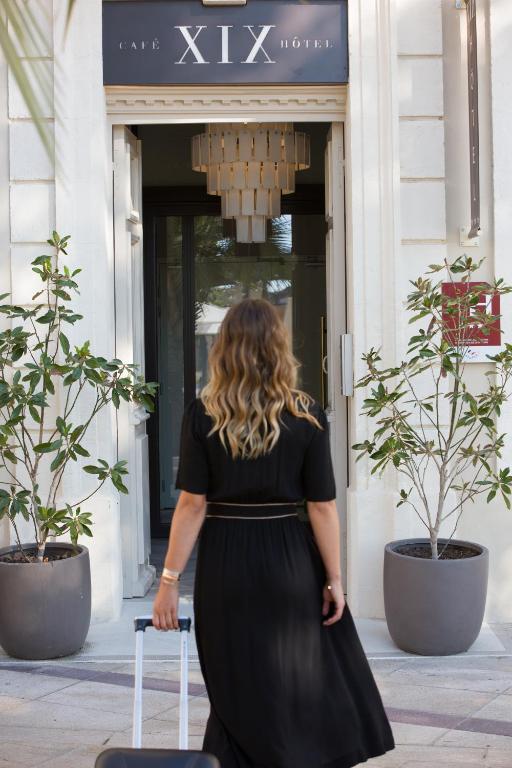a woman in a black dress standing in front of a building at Hôtel le XIX in Béziers
