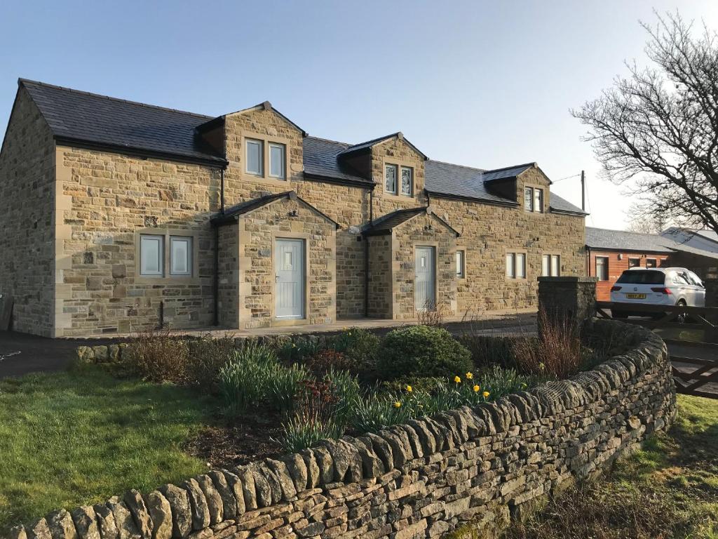 a brick house with a stone retaining wall at Pepperpot Cottage in Skipton