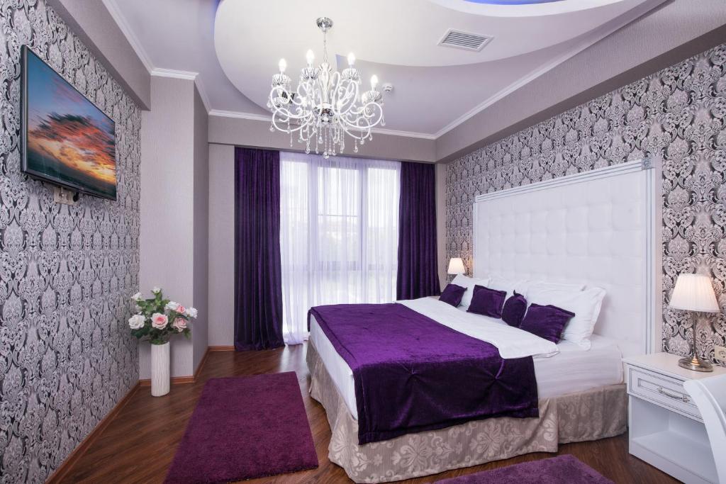 a bedroom with a large bed and a chandelier at Hotel De Paris in Krasnodar