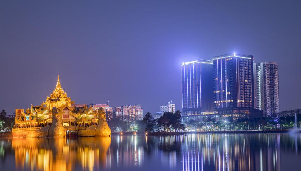 a city with a large building in the water at night at Wyndham Grand Yangon in Yangon