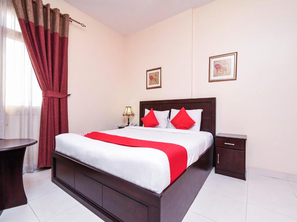 um quarto com uma cama grande e almofadas vermelhas em Paradise Inn 1 Tabasum Group em Ajman