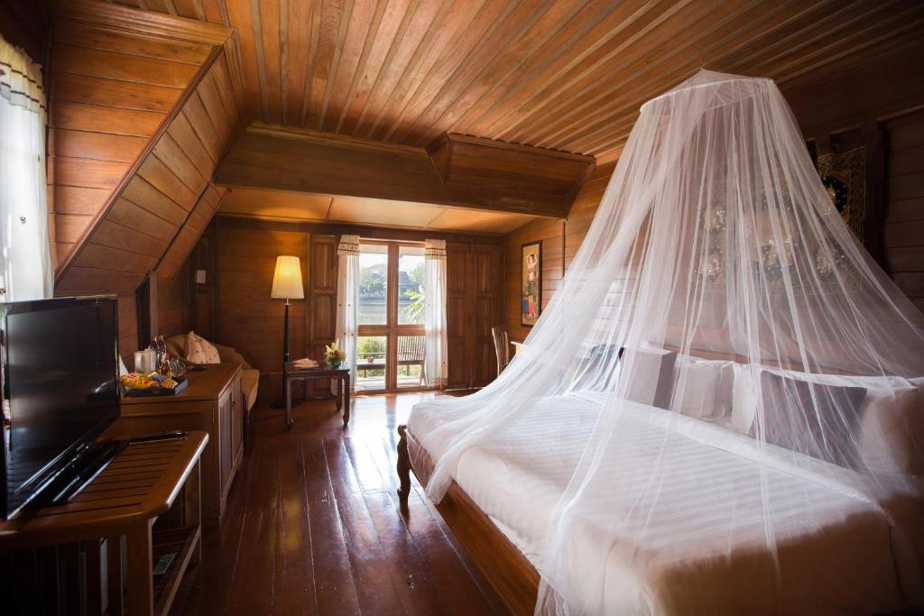 1 dormitorio con 1 cama con mosquitera en The Imperial River House Resort, Chiang Rai, en Chiang Rai