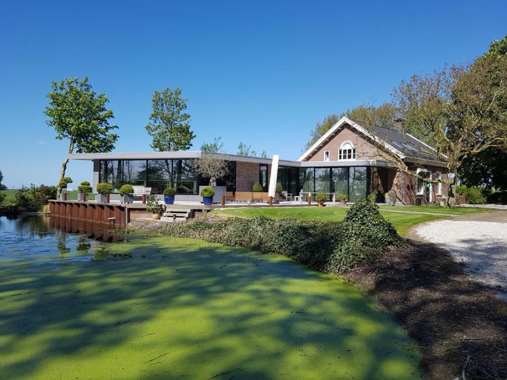 a large house with a lake in front of it at Hofstede Prinsland in Kortgene