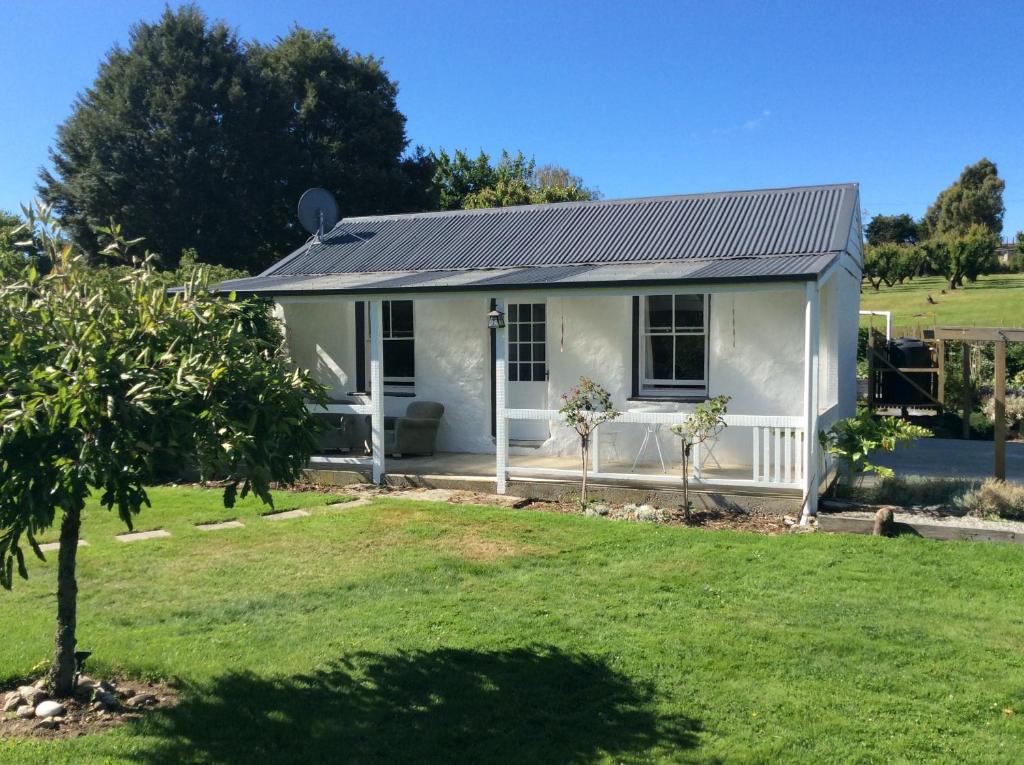 a small white house with a yard at Granny Stringer’s Cottage in Roxburgh
