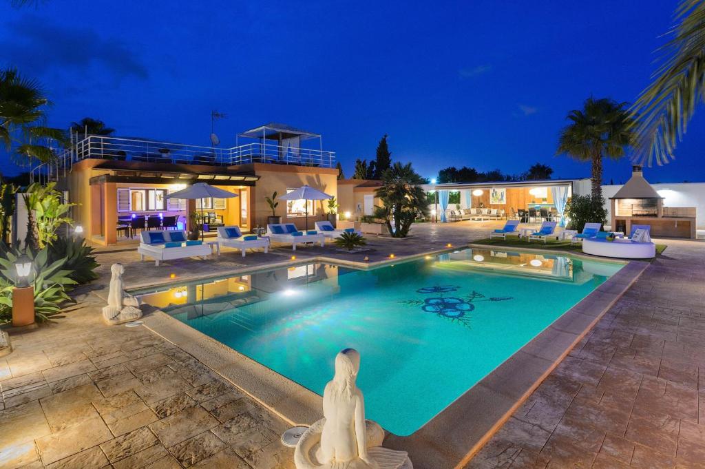 una piscina frente a una casa por la noche en Serena Villa en Ibiza