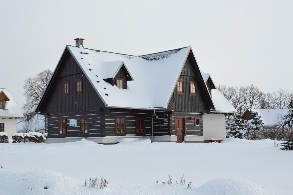 a black house with a snow covered roof at Chalupa FRED s infra saunou in Vrchlabí