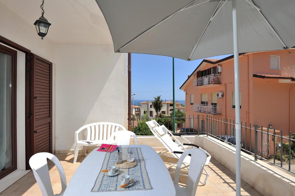 un tavolo bianco e sedie su un balcone con ombrellone di Casa Bianco Navarrese B a Santa Maria Navarrese