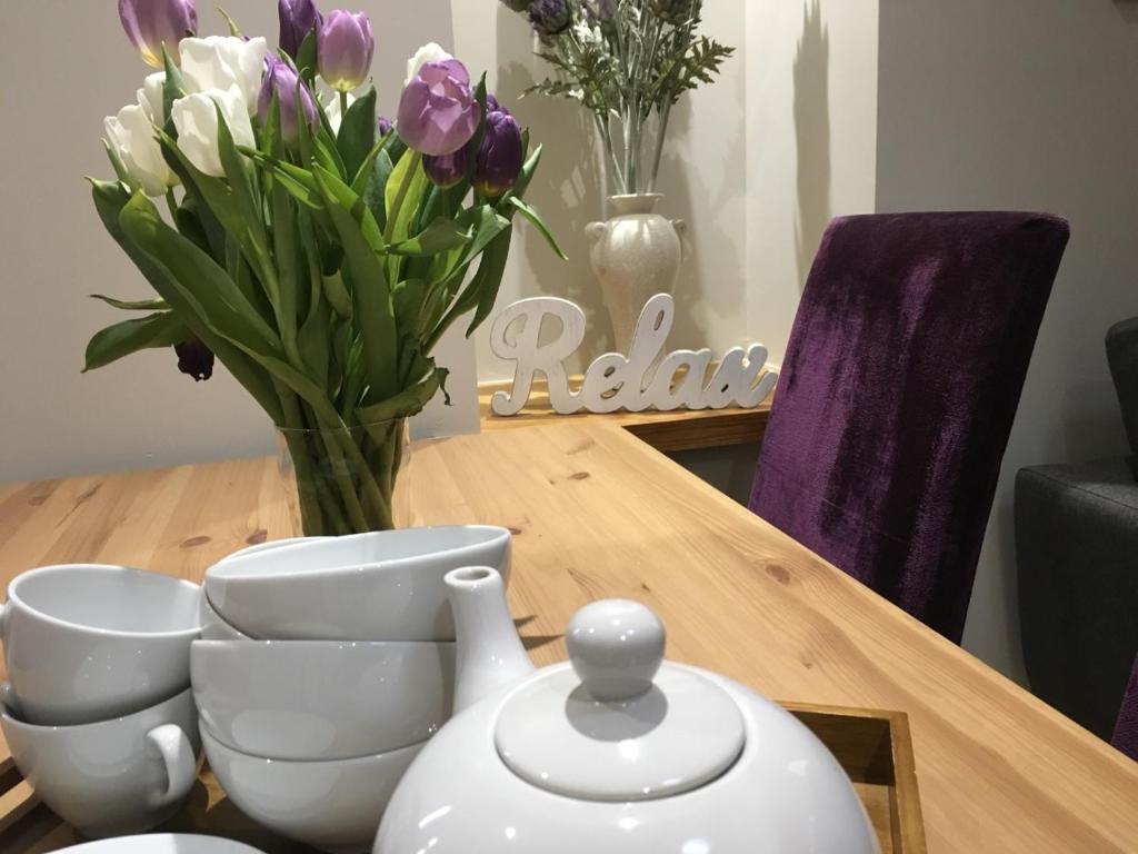 a dining room table with a white tea pot and flowers at Corran Cottage in Inverness